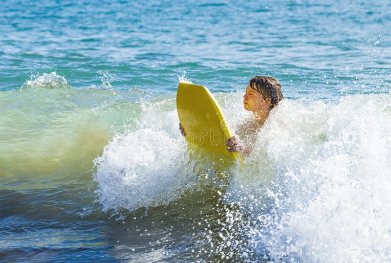 Teen boy has fun surfing in the waves