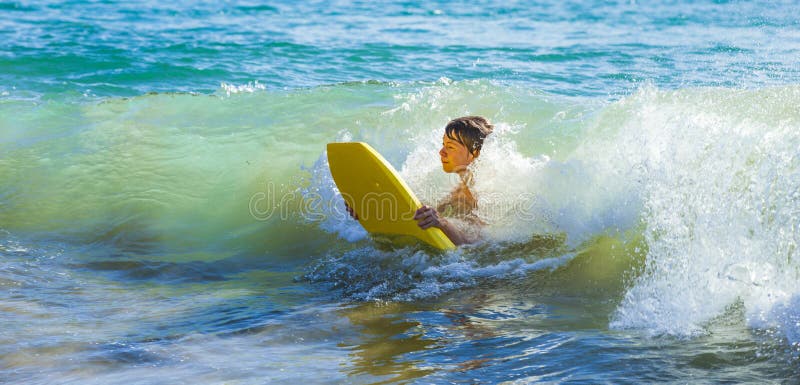 Teen boy has fun surfing in the waves