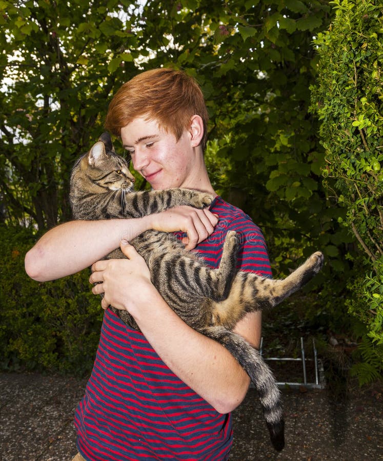 Teen boy and his tabby cat outside in the garden