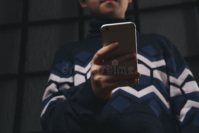 Teen boy holding phone and feeling sad. Victim of cyberbullying. Phone bullying.