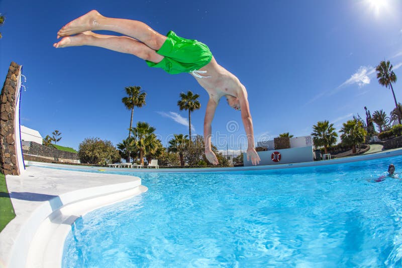 Teen boy jumping in the blue pool