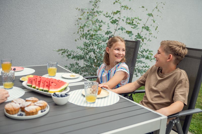 Teen brother and suster having breakfast outdoors stock photo