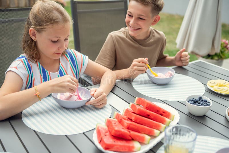 Teen brother and suster having breakfast outdoors stock image
