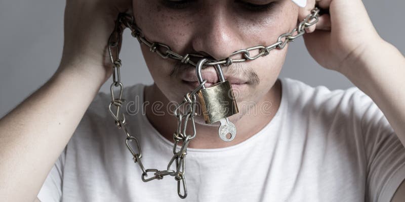 Teen covered mouth by rusty chain and lock to forbidden him the free speeching. Isolated on grey background