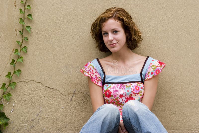 PIcture of a teen girl sitting against a stucco wall that includes ivy. PIcture of a teen girl sitting against a stucco wall that includes ivy.