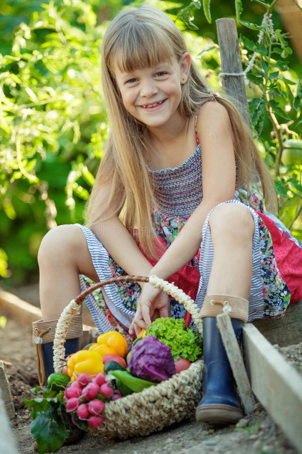 Teen girl collects vegetables in their garden.