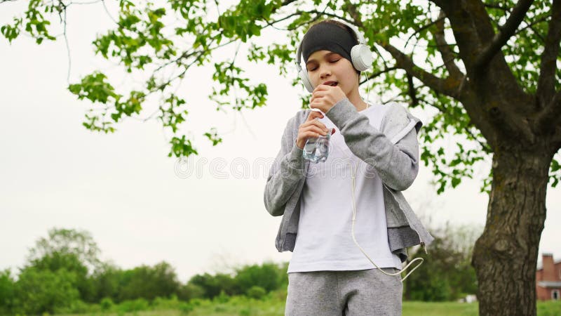 Teen girl in headphones drink water after Jogging