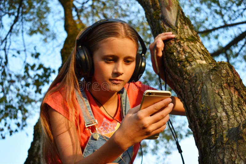 Teen girl in headphones looks at phone royalty free stock image Teen girl in headphones looks at phone royalty free stock image