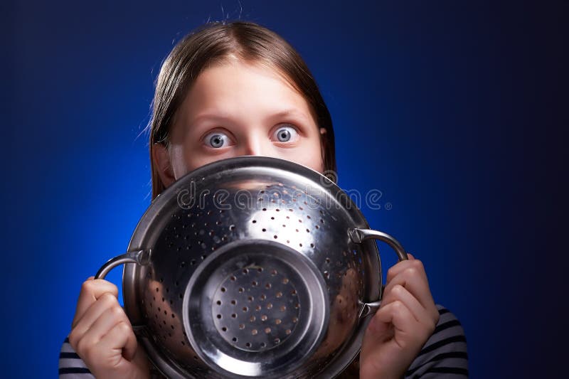 Shocked teen girl hiding her face behind colander