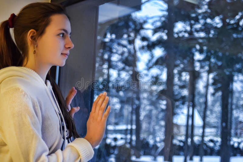 Teen girl looking out the window with a winter landscape