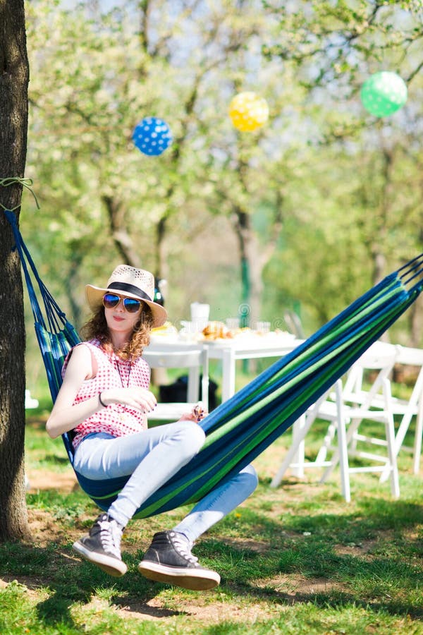 Teen girl sitting in hammock on garden party and eating cake stock photography Teen girl sitting in hammock on garden party and eating cake stock photography