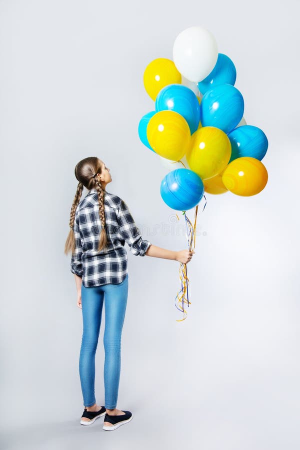Teen girl standing back holding a bunch of balloons stock image Teen girl standing back holding a bunch of balloons stock image