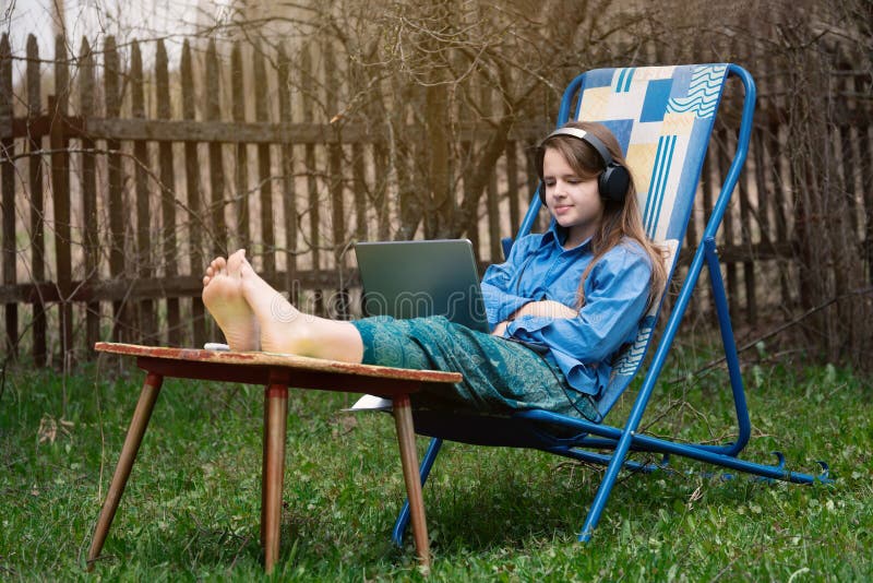 Teen girl takes part in a school online webinar sitting outdoors in springtime