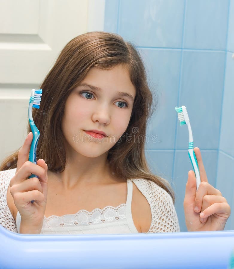 Teen girl to decide between the two toothbrushes