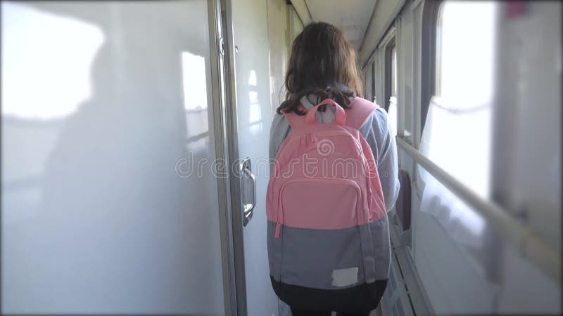 Teen girl walks on a train compartment car with lifestyle a backpack. Travel transportation railroad concept.Little