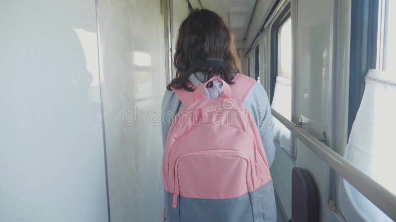 Teen girl walks on a train compartment car with lifestyle a backpack. Travel transportation railroad concept.Little