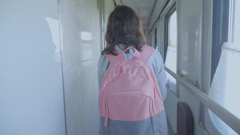 Teen girl walks on a train compartment car with lifestyle a backpack . travel transportation railroad concept.little