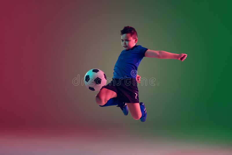 Teen male football or soccer player, boy on gradient background in neon light - motion, action, activity concept