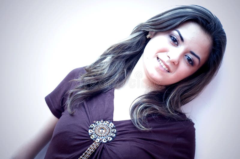 Young teen model stands against a white background. She has long brunette hair and wearing a brown shirt. Image is diagonally oriented.