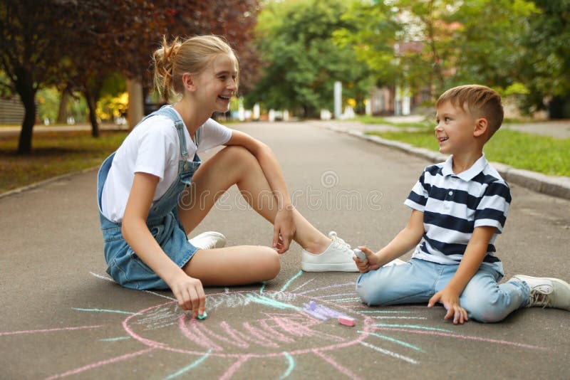 Teen nanny and cute little boy drawing sun with chalks royalty free stock photography Teen nanny and cute little boy drawing sun with chalks royalty free stock photography