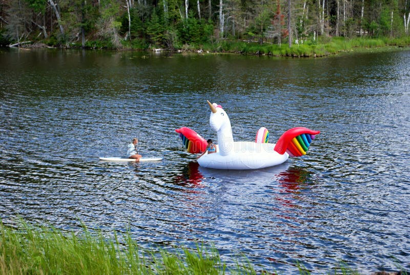 Teen paddle boarding to a huge inflatable unicorn floaty in the middle of a lake upper peninsula michigan