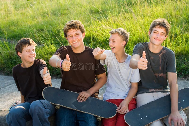 Group of teen boys resting on playground after playing skateboard. Group of teen boys resting on playground after playing skateboard