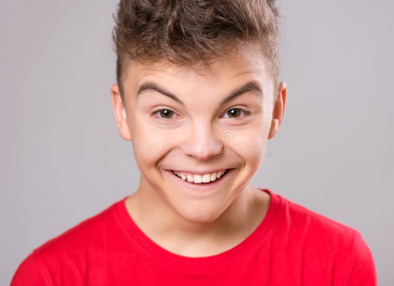 Silly teen boy making grimace - funny face. Child on gray background. Emotional portrait of caucasian teenager looking at camera. Silly teen boy making grimace - funny face. Child on gray background. Emotional portrait of caucasian teenager looking at camera.
