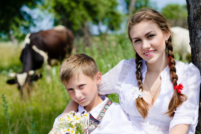 Teen Sister And Little Brother Sitting By Cow Herd Stock Photo Image
