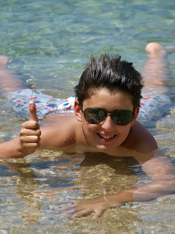 Portrait of a charming teen with sunglasses lying in Adriatic sea (Dalmatia-Croatia) showing thumbs up sign. Vertical color photo. Portrait of a charming teen with sunglasses lying in Adriatic sea (Dalmatia-Croatia) showing thumbs up sign. Vertical color photo.