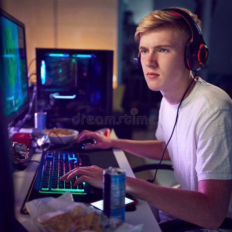 Teenage Boy die hoofdtelefoon aan huis gokken gebruikend de Dubbele Schermen van de Computer