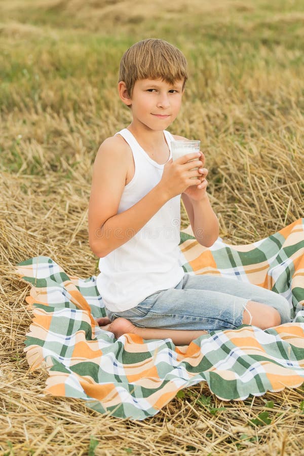 Teenage boy drinking fresh raw milk from glass. 