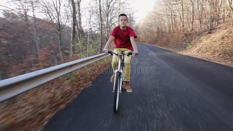 Teenage boy riding his bike on autumn forest road - timelapse