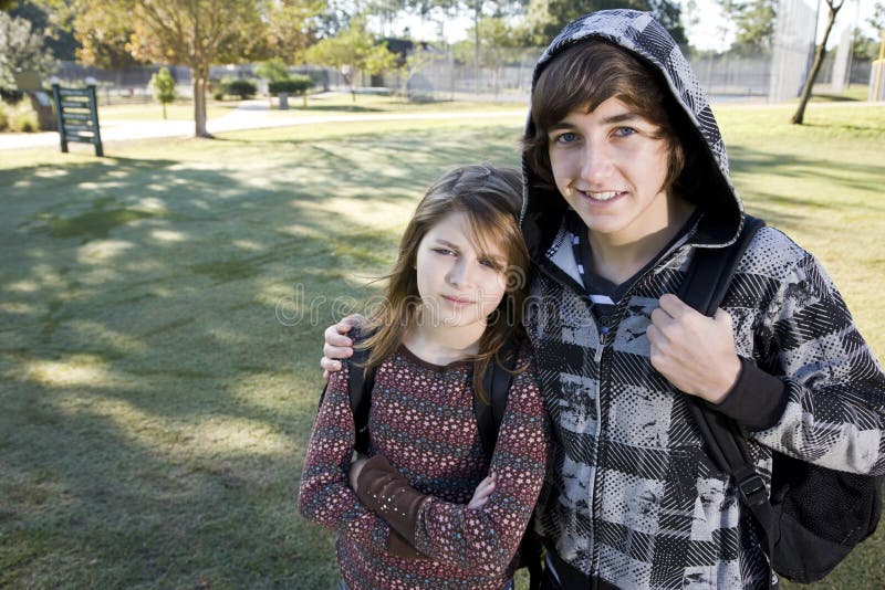 Teenage boy and young sister with school backpacks