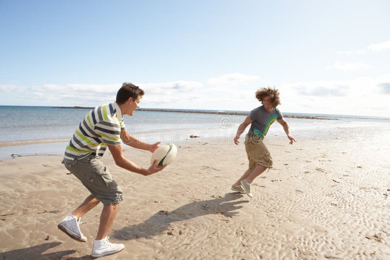 Teenage Boys Playing Rugby On Beach