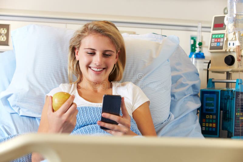 Teenage Female Patient Using Mobile Phone In Hospital Bed