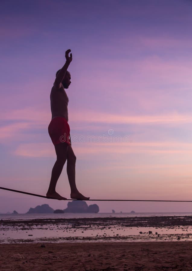 Teenage girl balancing on slackline with sky view on the beach