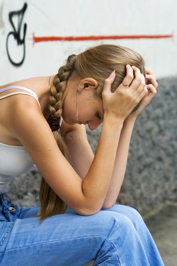Ragazza adolescente in depressione seduto su un marciapiede.