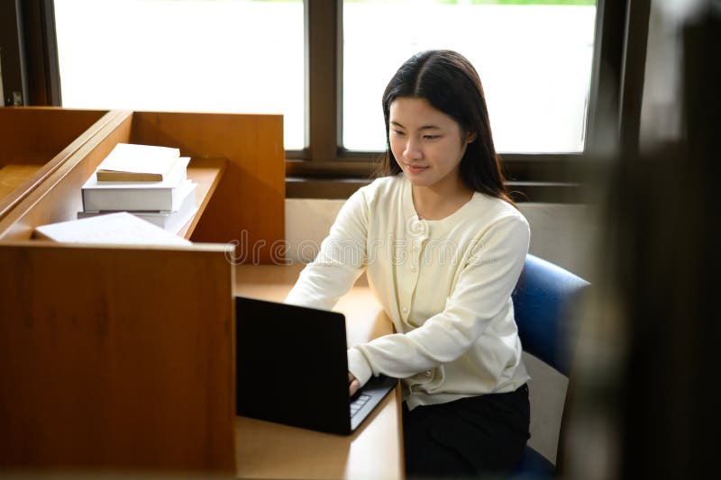 Teenage girl education concept. Her using laptop in library royalty free stock photography