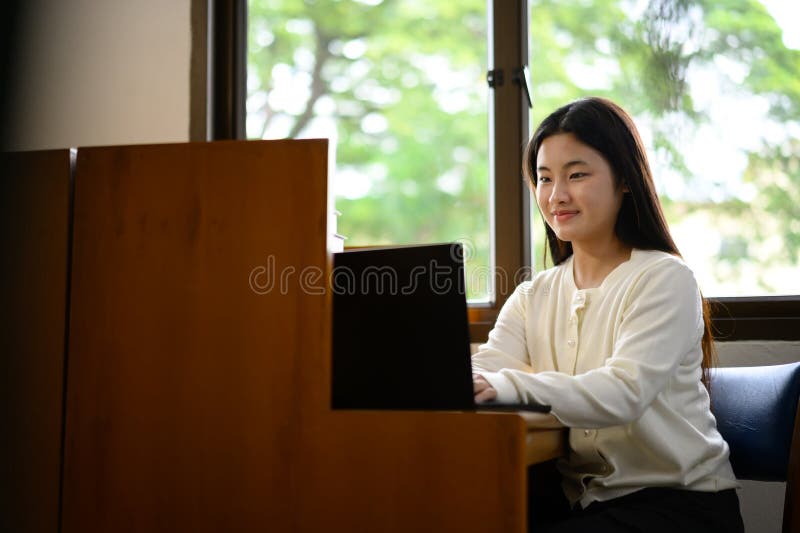 Teenage girl education concept. Her using laptop in library stock photography