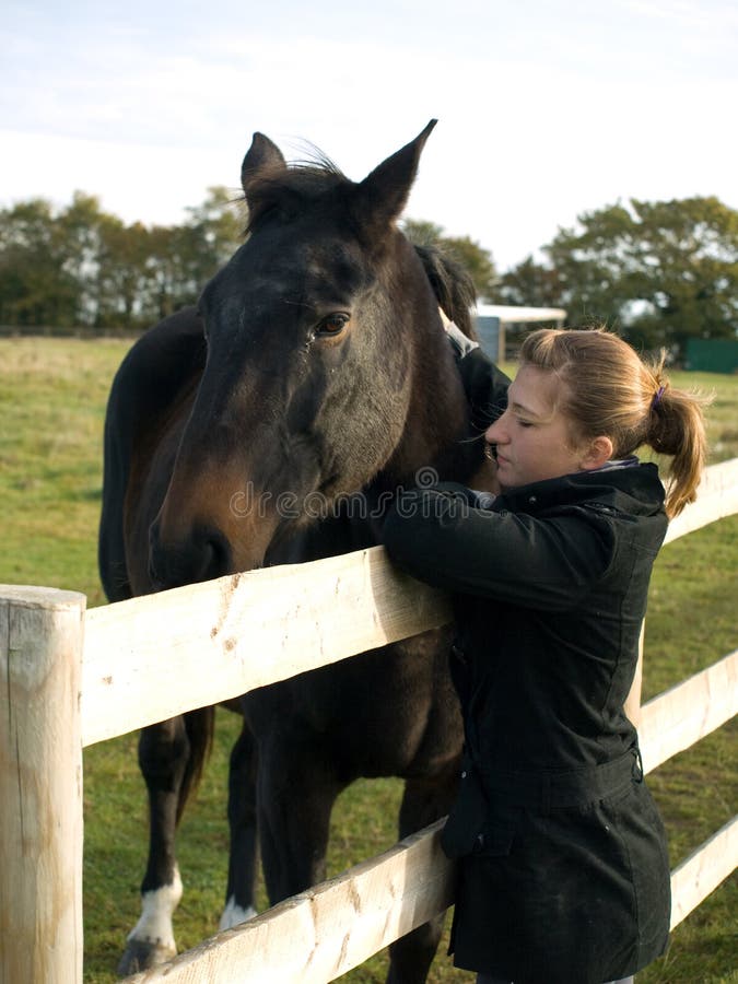 Teenage girl with a horse in a field