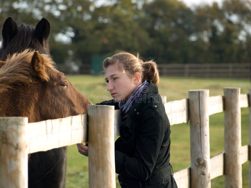 Teenage girl with a horse in a field