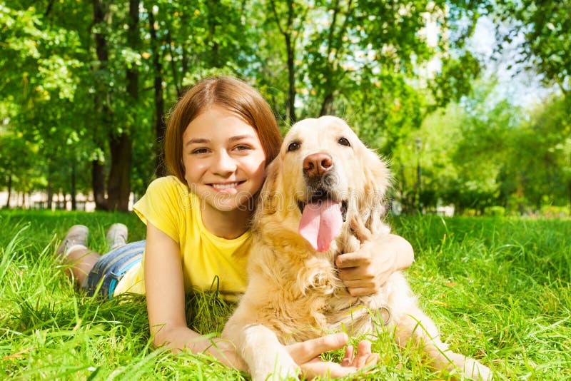 Teenage girl laying with her pet dog in park