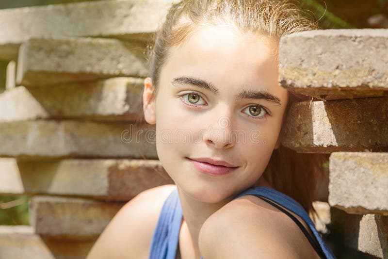 Teenage girl leaning against a stack of flagstones