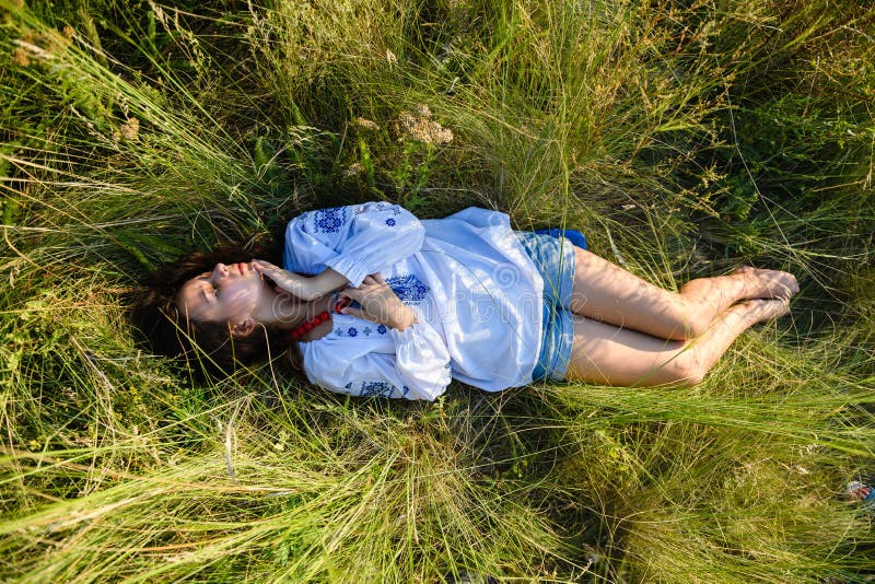 A teenage girl lies in a tall meadow grass