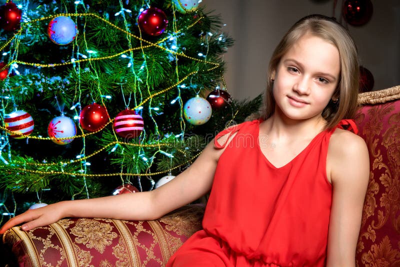 A teenage girl is sitting near the New Year tree. royalty free stock images
