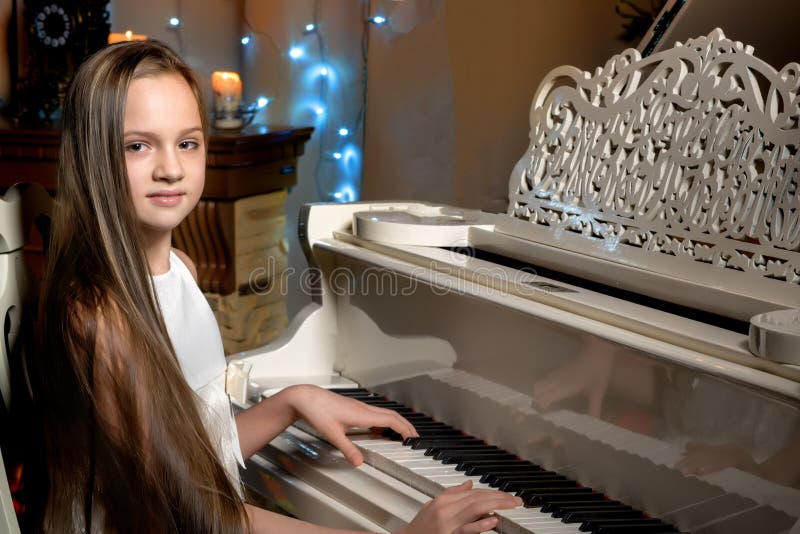 A teenage girl plays a piano on a Christmas night by candlelight royalty free stock images