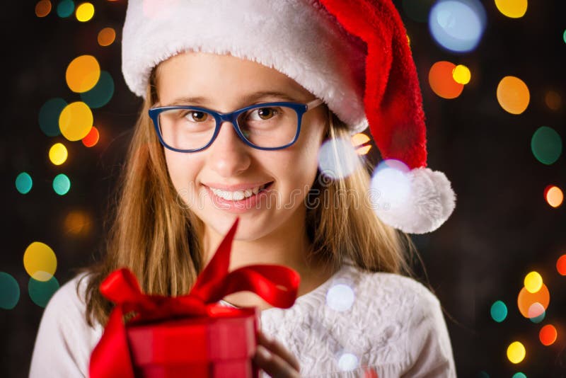 Teenage girl with Santa hat holding a present stock photo Teenage girl with Santa hat holding a present stock photo