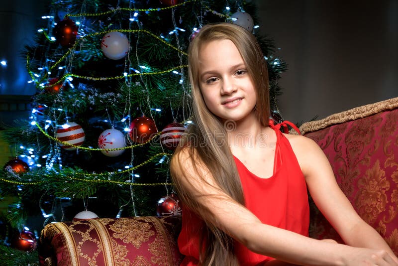 A teenage girl is sitting near the New Year tree. royalty free stock image