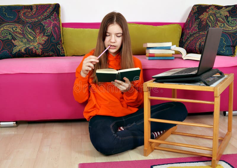 Teenage girl studies with a laptop and a book royalty free stock photography Teenage girl studies with a laptop and a book royalty free stock photography