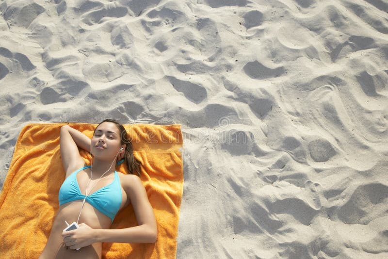 Teenage Girl Using MP3 Player Lying On Beach Towel